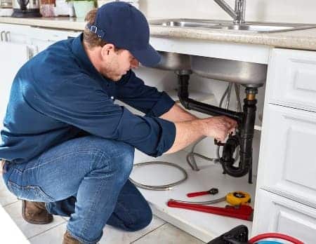 plumber at work under kitchen sink