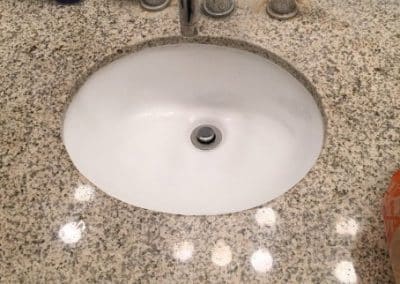 White sink installation in brown marble counter by RT Olson Plumbing