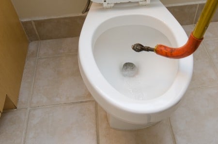 snaking a toilet drain with drain auger
