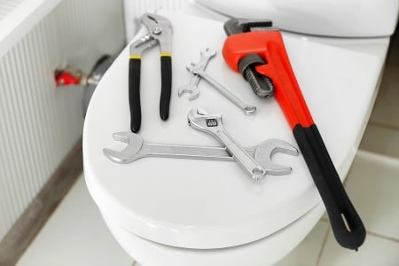 plumber tools on top of a toilet to replace